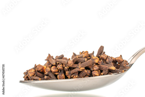 Dry aromatic cloves in a metal spoon, macro, isolated on a white background.