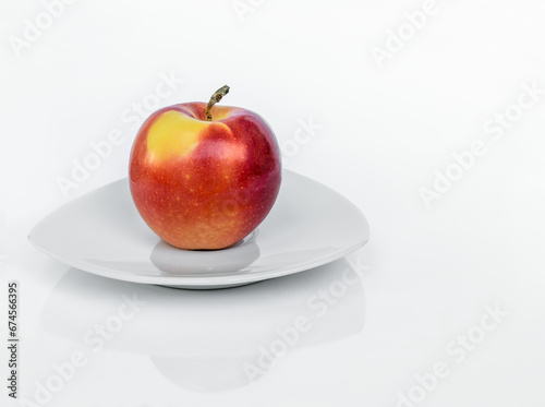 Ripe Gala apple on a porcelain plate isolated on a white