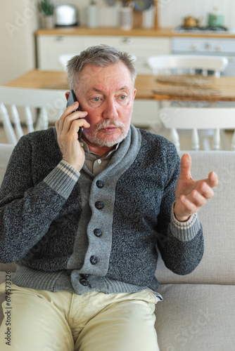 Happy middle aged senior man talking on smartphone with family friends. Older mature grandfather with cell phone talking with grown up children, resting at home. Older generation modern tech usage