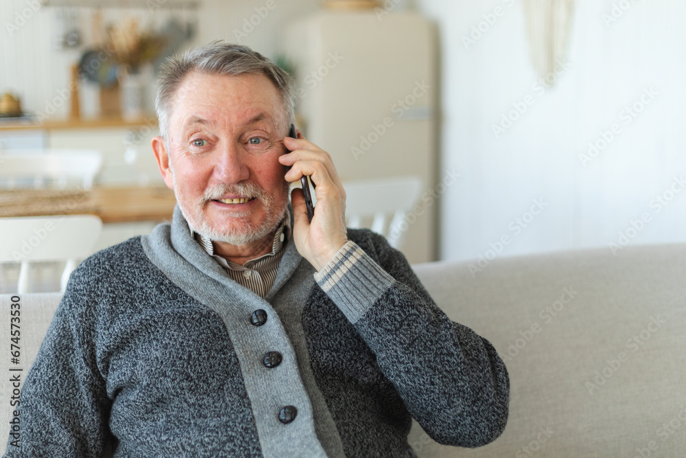 Happy middle aged senior man talking on smartphone with family friends. Older mature grandfather with cell phone talking with grown up children, resting at home. Older generation modern tech usage