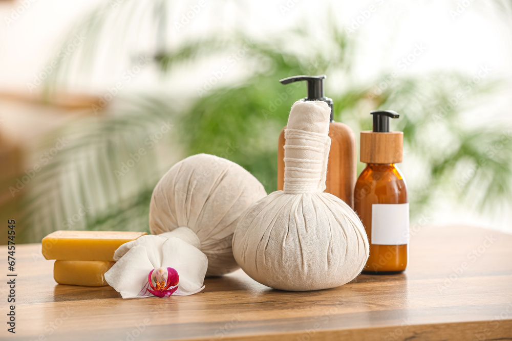 Herbal massage bags, bottles of cosmetic products and soap bars on wooden table - obrazy, fototapety, plakaty 