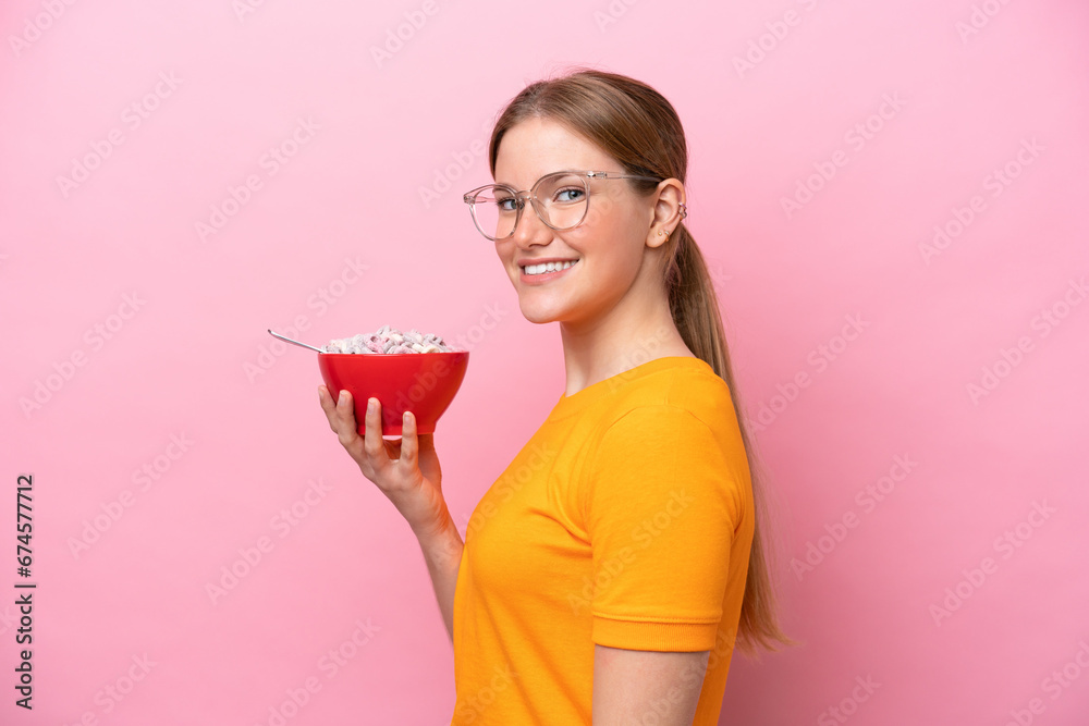 Young caucasian woman holding a bowl of cereals isolated on pink background smiling a lot Young caucasian woman holding a bowl of cereals isolated on pink background smiling a lot