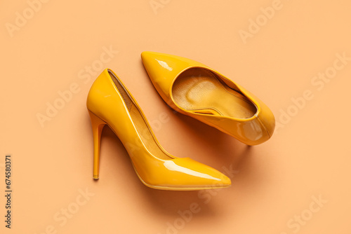 Stylish yellow high heels on brown background
