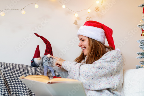 Immaturity, infantile. Young adult woman reads a fairy tale while Christmas and playing with kids toy gnomes.