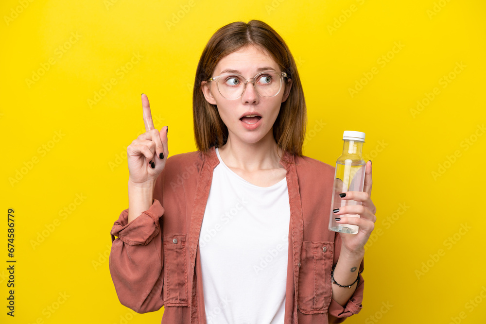 Young English woman with a bottle of water isolated on yellow background thinking an idea pointing the finger up Young English woman with a bottle of water isolated on yellow background thinking an idea pointing the finger up