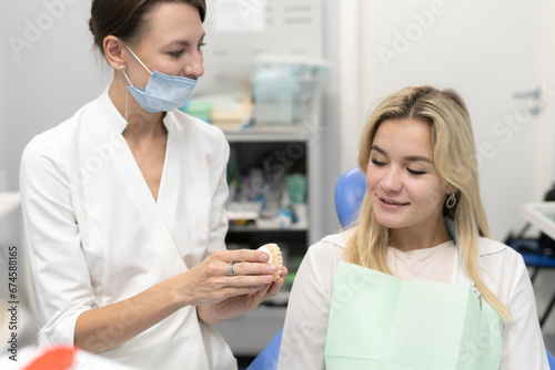 female orthodontist talking to client in the clinic and shows her mold of jaw