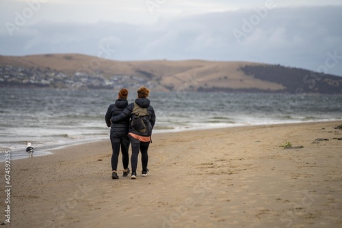 lesbian couple walking together on a sandy beach