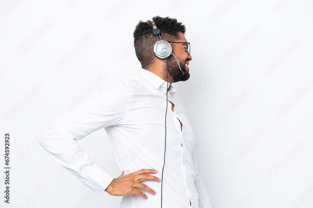 Telemarketer Brazilian man working with a headset isolated on white background suffering from backache for having made an effort Telemarketer Brazilian man working with a headset isolated on white background suffering from backache for having made an effort