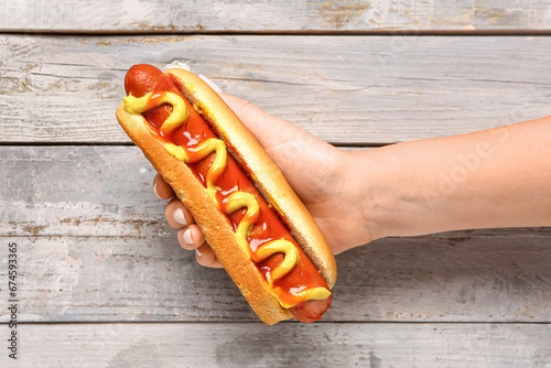 Woman holding tasty hot dog...