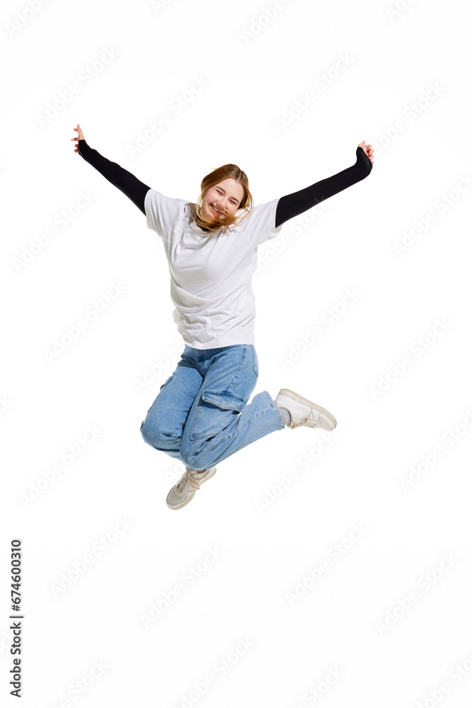 happy cheerful and cute young girl, jumping and raised hands of joy isolated white studio background. Concept of beauty, youth, human emotions, fashion, style, modelling. Copy space for ad, text.