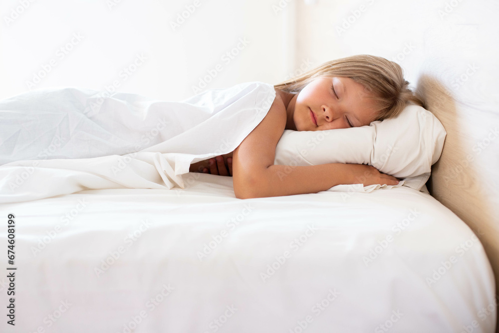 A little girl with long hair is peacefully sleeping in a comfortable bed on a white pillow at the morning. Front wide shot.It's perfect for projects related to family, childhood, or relaxation. A little girl with long hair is peacefully sleeping in a comfortable bed on a white pillow at the morning. Front wide shot.It's perfect for projects related to family, childhood, or relaxation.