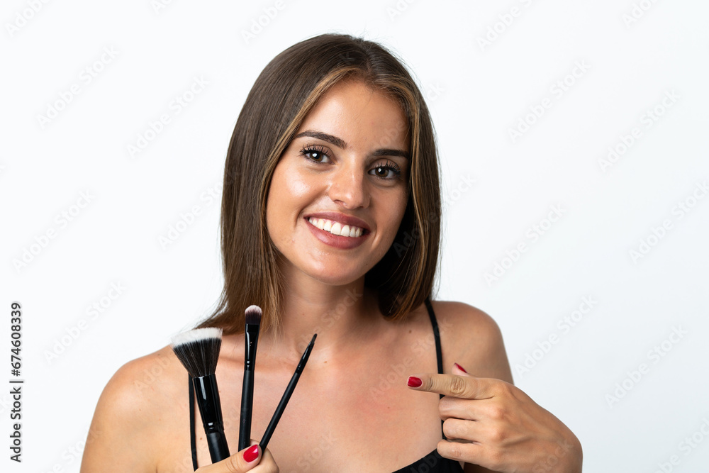 Young Uruguayan woman isolated on white background holding makeup brush and pointing it Young Uruguayan woman isolated on white background holding makeup brush and pointing it