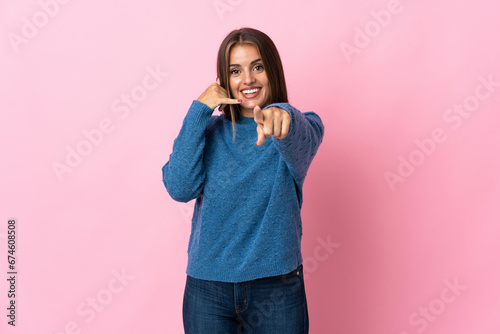 Young Uruguayan woman isolated on pink background making phone gesture and pointing front
