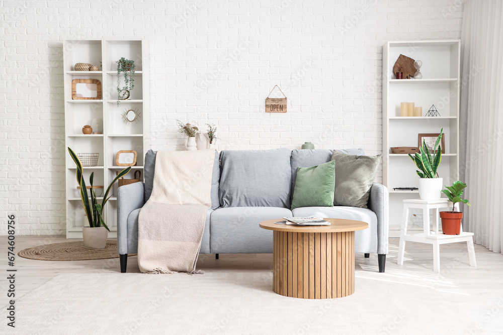 Fototapeta premium Interior of light living room with sofa, table and houseplants