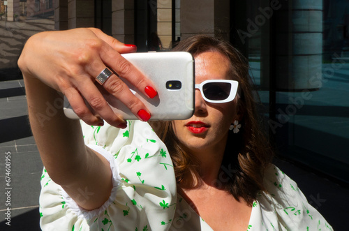 Woman make selfie with smartphone in paris, france. Woman with mobile phone on colorful background. Girl in sunglasses with fashion look and sensual beauty. New technology and modern life. High