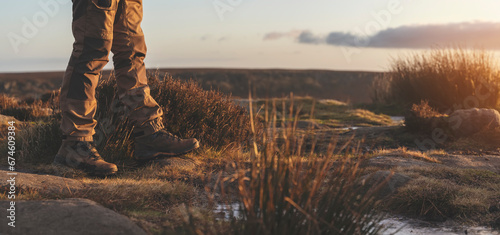 man in special boots walking in the mountains reaching the destination and on the top of mountain in Peak District at sunset on autumn day Travel Lifestyle concept