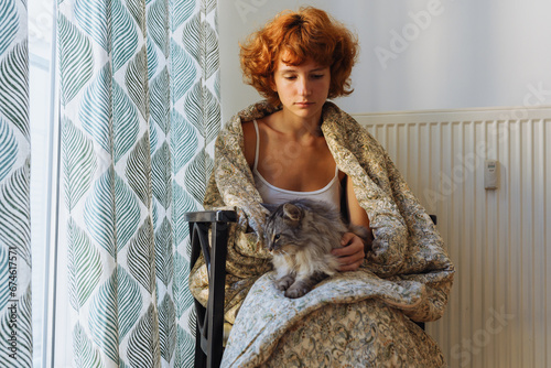 Tela Girl hugging cat, sitting in blanket at home, frozen