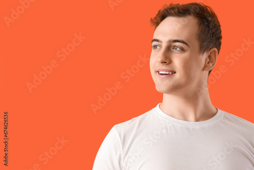 Smiling young man on orange background, closeup