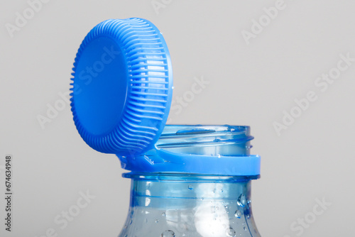 Foto Close up of new cap attached to plastic bottle, connected to the neck of the bottle by solid tab attached to safety ring