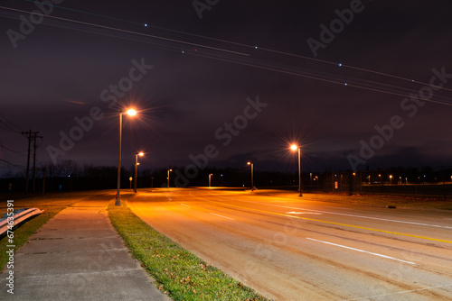 Airplane Light Trails in Cloudy Night Sky over Road