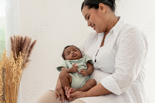 Portrait image an Asian mother happy and smile while holding a 1-month-old baby newborn son who is sleeping happily on his mother's chest, to relationship in family and baby newborn concept. photo