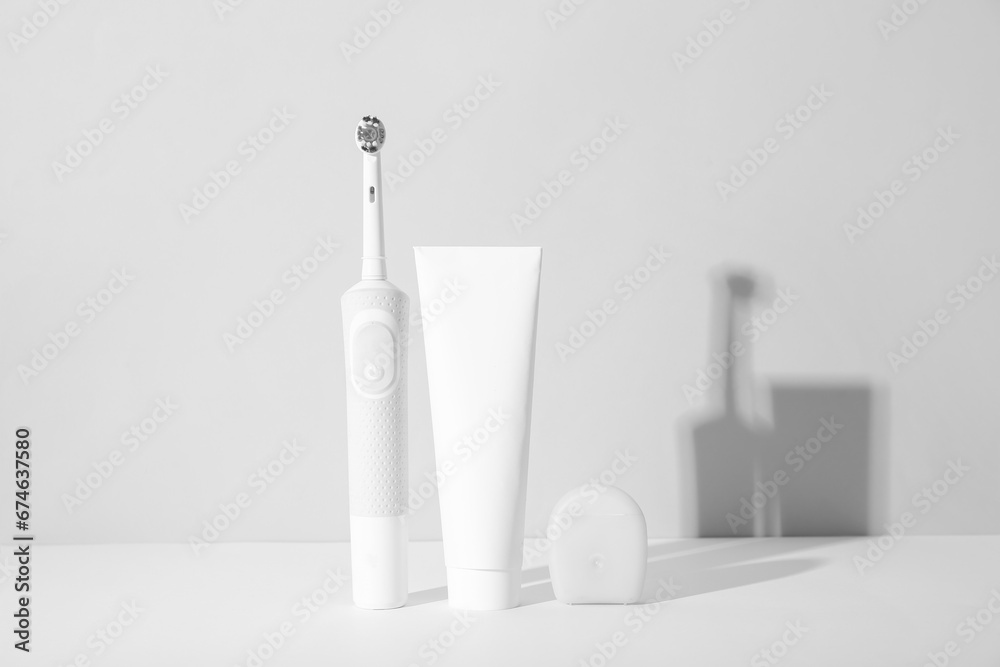 Electric toothbrush with toothpaste and dental floss on white background. - obrazy, fototapety, plakaty 