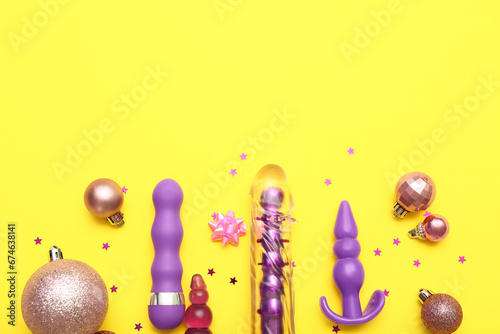Sex toys and Christmas balls on yellow background