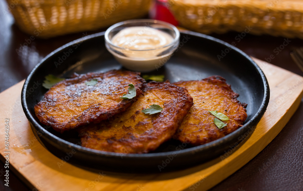 Fried grated potato pancakes with sour cream on frying pan Fried grated potato pancakes with sour cream on frying pan