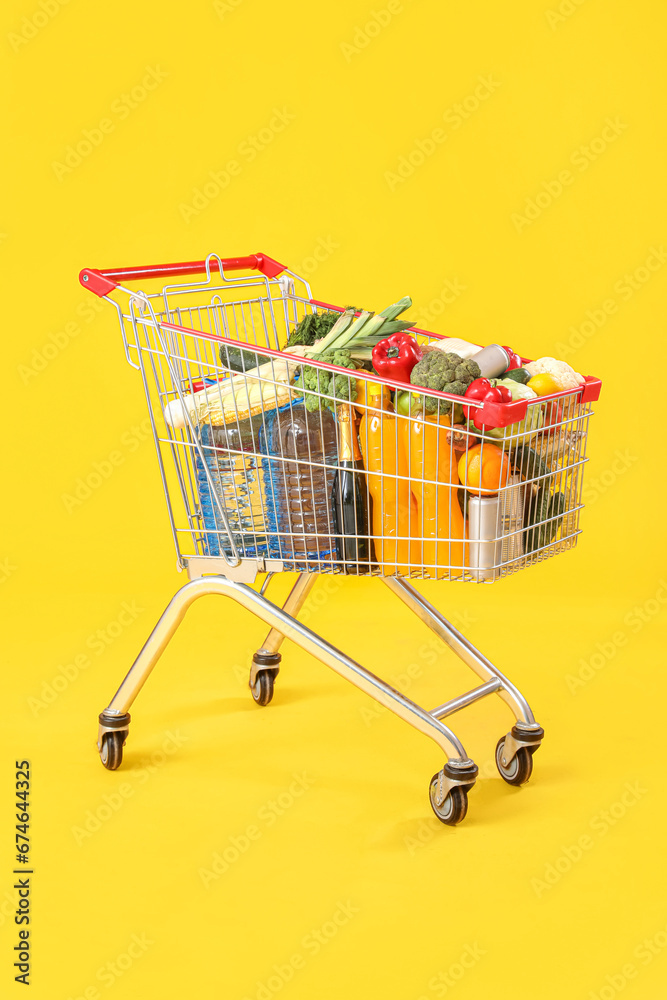 Shopping cart full of food on yellow background