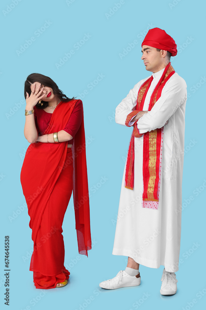 Sad Indian couple after quarrel on blue background