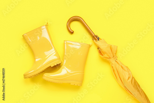 Schilderij op canvas Yellow stylish umbrella and gumboots on color background