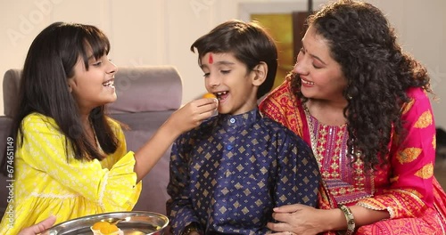 Girl giving her brother bite of laddu on Rakshabandhan
