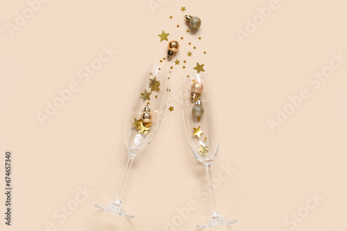 Beautiful composition with champagne glasses and decorations for New Year party on beige background © Pixel-Shot