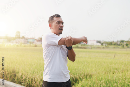 Asian man stretching outdoors before morning run on the street