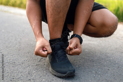 Adult Asian man tying his shoelaces and getting ready to go jogging and exercising outside