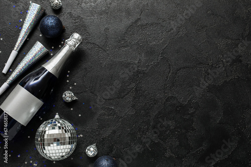 Beautiful composition with bottle of champagne and decorations for New Year party on black background
