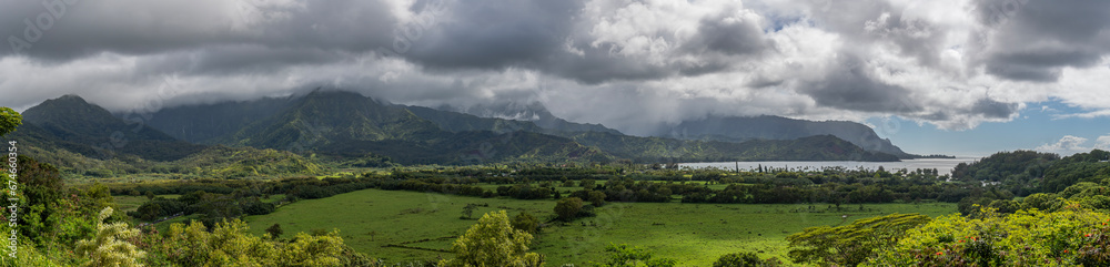 Fototapeta premium A panoramic view from the Hanalei Bay Lookout of the lush valley, mountains and the Pacific Ocean in Kauai, Hawaii, United States. 