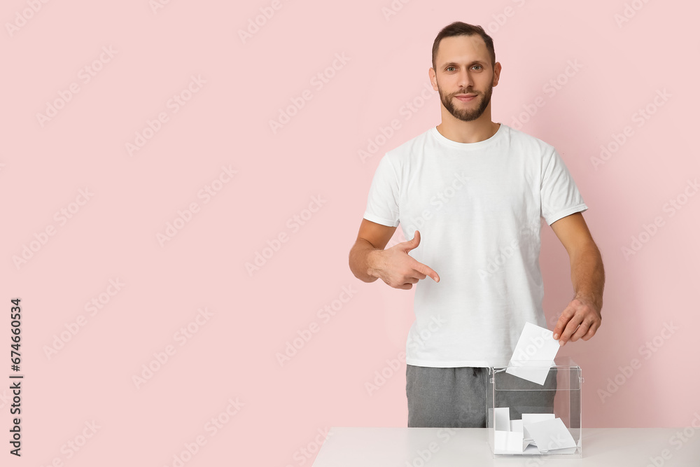 Voting man pointing at ballot box on pink background Voting man pointing at ballot box on pink background