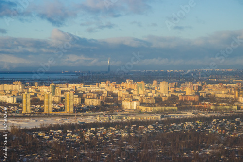 Aerial view of the city of St. Petersburg. Winter cityscape. In the foreground is a village and high-rise buildings. A tall skyscraper in the distance. Big northern city. Saint-Petersburg, Russia.