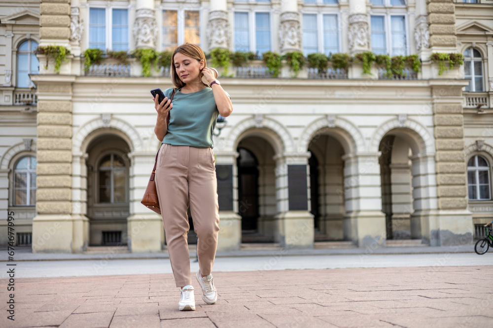 Shot of an attractive young businesswoman standing alone outside and using her cellphone.