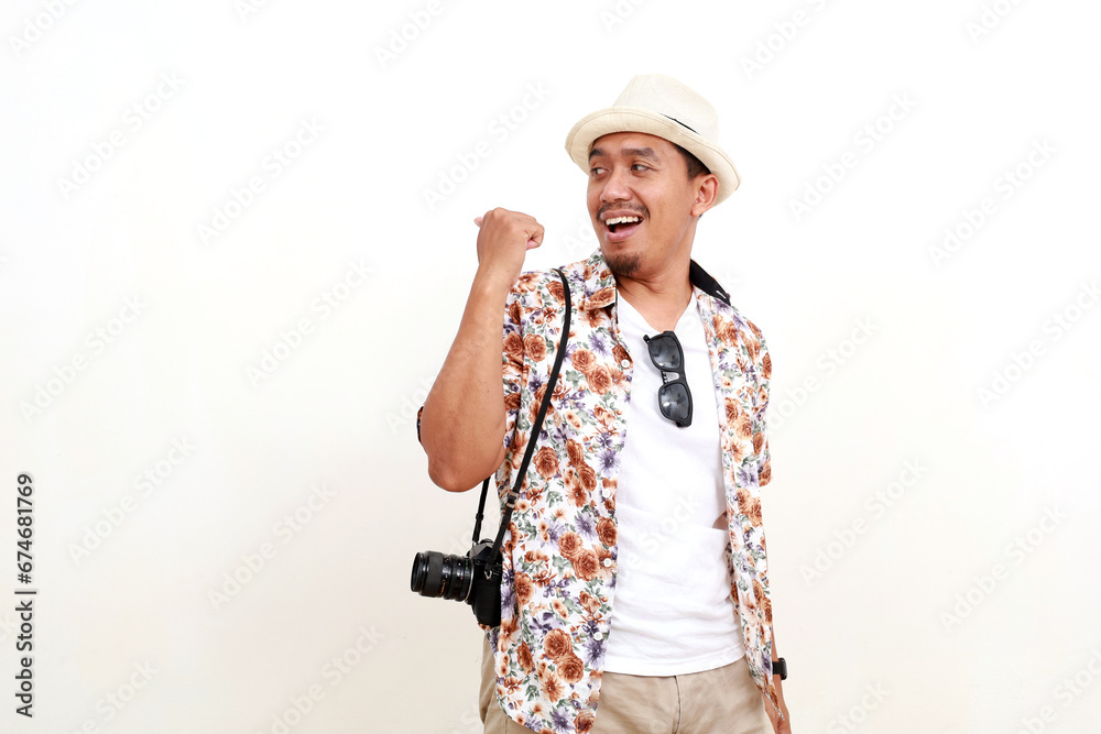 Happy Asian adult man tourist standing while pointing something on empty space. Concept of travel. Isolated on white background