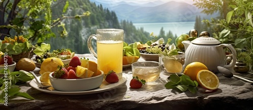 In the background of a picturesque nature setting a table was set with healthy food options like fresh fruits and vegetables accompanied by a glass of refreshing green tea infused with lemon