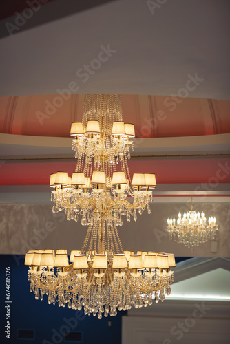 A contemporary chandelier, is a branched ornamental light fixture designed to be mounted on ceilings. Beautiful classic chandelier hanging on the ceiling, conical lampshades for the chandelier.