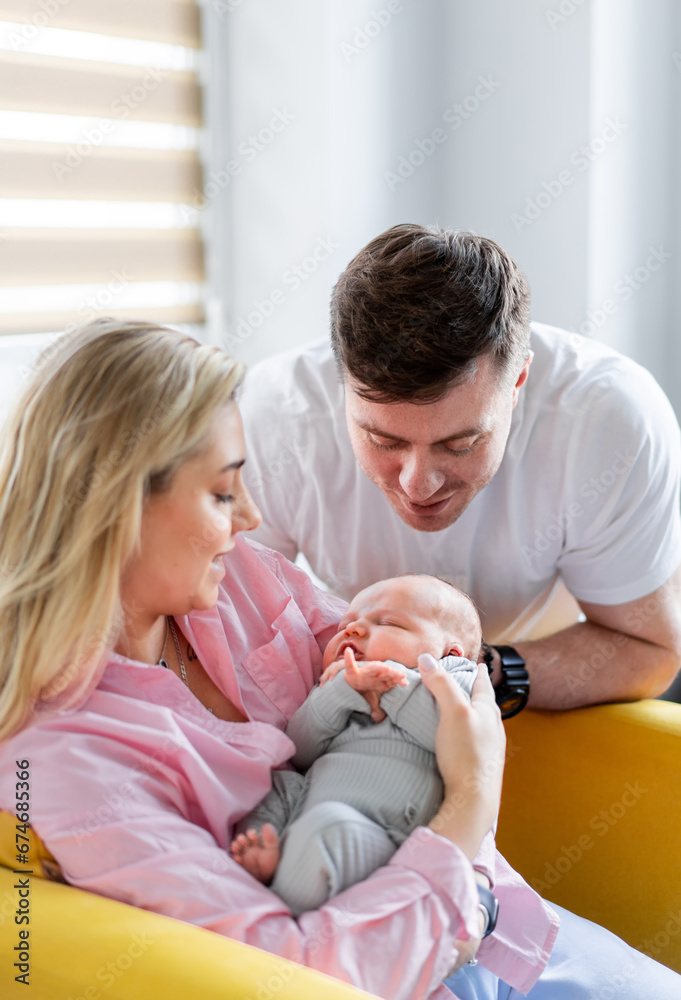 A man and woman holding a baby on a couch. A Joyful Family Moment on the Comfortable Living Room Sofa A man and woman holding a baby on a couch. A Joyful Family Moment on the Comfortable Living Room Sofa