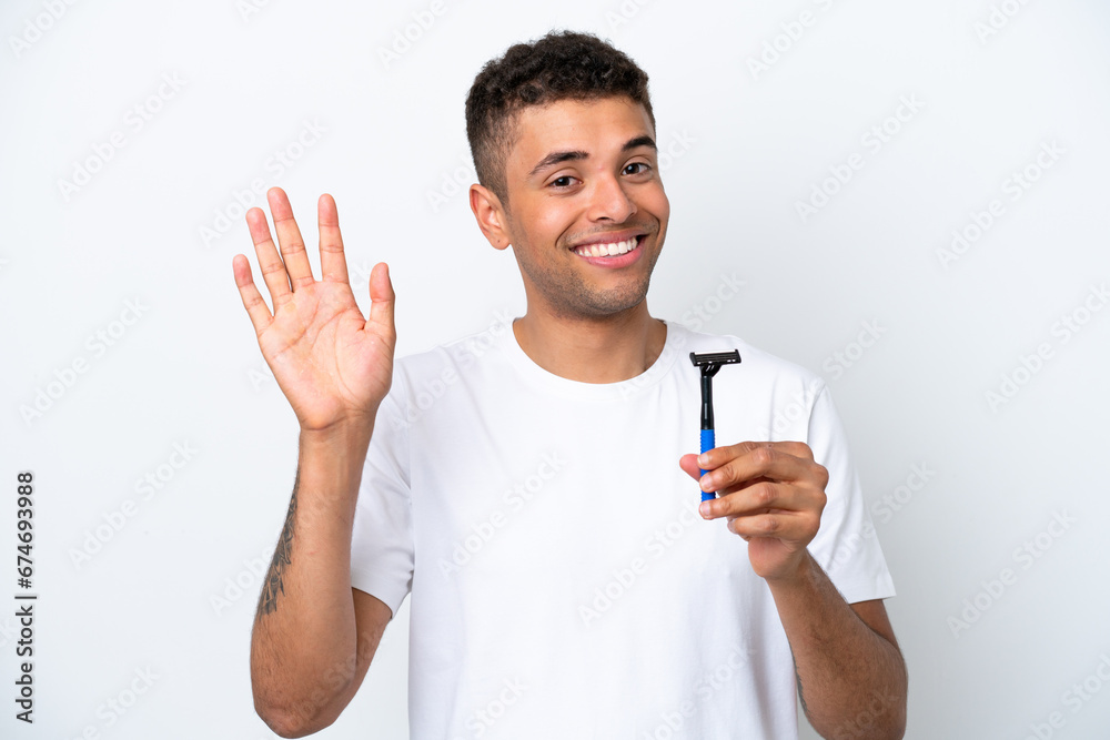 Young Brazilian man shaving his beard isolated on white background saluting with hand with happy expression Young Brazilian man shaving his beard isolated on white background saluting with hand with happy expression