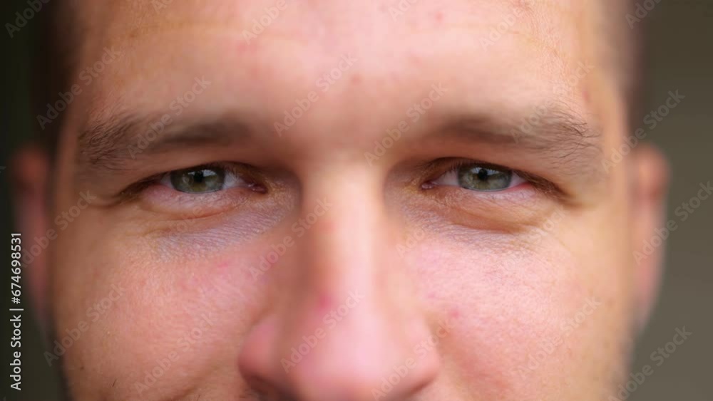 Extreme close up of handsome young man face looking at camera and smiling. Positive emotions. Caucasian guy smiles in good mood. Male eyes with deep look. Real time concept.