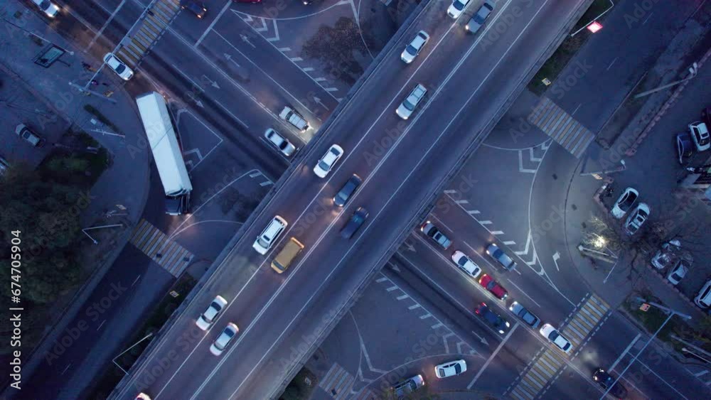 A busy intersection with a lot of cars, buses and trucks. Aerial view from the drone on the night road, the city and pedestrians. Lights and headlights are shining. A traffic jam has formed. Almaty