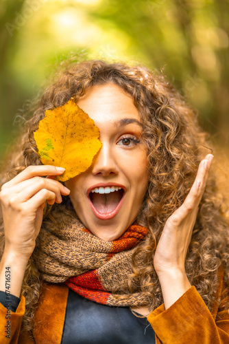 Playful woman hiding among yellow leaf