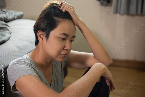 Asian woman's struggle, reflecting the depths of her despair. The sunlight through the window, casting the bedroom floor where she sits and expresses emotional sorrow, depression, anxiety and lonely.