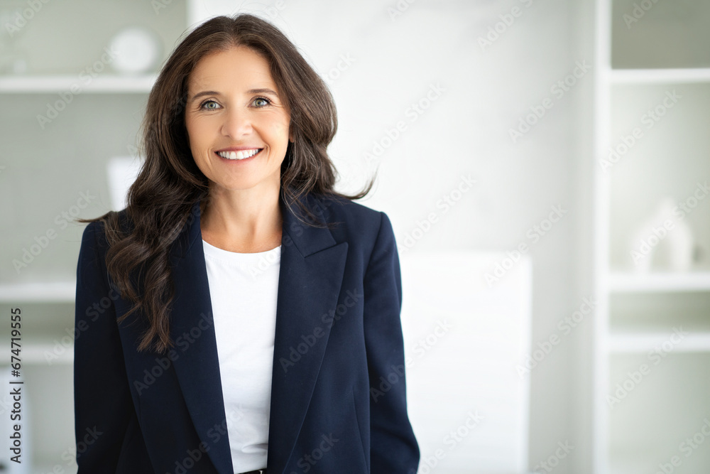 Cheerful middle aged woman manager posing in modern office Cheerful middle aged woman manager posing in modern office